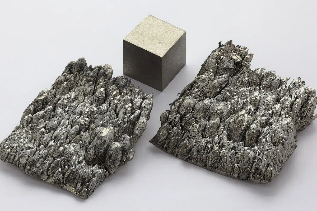 Scandium sublimé-dendritiques pur à 99,998 % placé à côté d'un cube d'1cm d'arête de scandium refondu à l'arc.