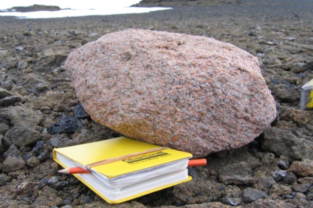 Un bloc de granite rose posé à côté d’un carnet jaune servant d’échelle. Crédit : Jo Johnson, BAS. 