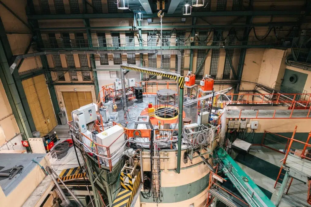 Le réacteur de recherche LVR-15, exploité par CVŘ Řež en République tchèque, sert de véritable laboratoire nucléaire pour tester matériaux, combustibles et équipements sous bombardement neutronique intense. Son cœur comprend plusieurs zones d’irradiation spécialisées : positions directement dans le combustible pour les flux neutroniques les plus élevés, canaux installés dans le réflecteur en béryllium, systèmes pneumatiques « Rabbit » capables de transporter rapidement des échantillons irradiés, ou encore canaux rotatifs assurant une exposition homogène aux neutrons.
Ces installations permettent de reproduire en accéléré les conditions extrêmes rencontrées dans les réacteurs nucléaires civils ou certains programmes de recherche avancés. Dans certaines zones du LVR-15, le flux neutronique atteint jusqu’à 5 × 10¹³ neutrons par centimètre carré et par seconde, un environnement suffisamment agressif pour tester la résistance des matériaux destinés aux futures générations de réacteurs. crédit : Czech International Centre of Research Reactors