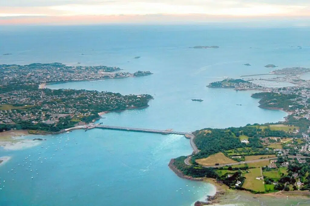 Vue aérienne du barrage et usine marémotrice de La Rance avec en arrière plan Saint-Malo à droite de l'estuaire.