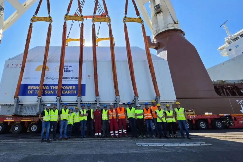 Photo de groupe lors du chargement de la caisse du récipient sous vide sur le navire qui la transportera dans le sud de la France. Septembre 2026. ©F4E